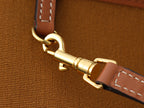 Gold tone swivel clasp on brown strap with stitched edge