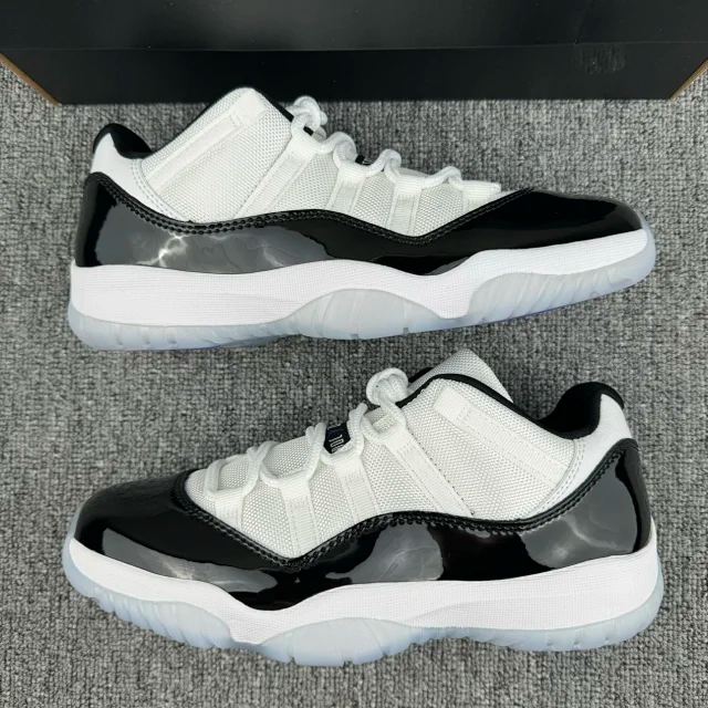Pair of white and black low-top sneakers with textured sole and black glossy toe