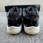Jordan 11 sneakers with black upper, red Jumpman on heel, white midsole, cream outsole