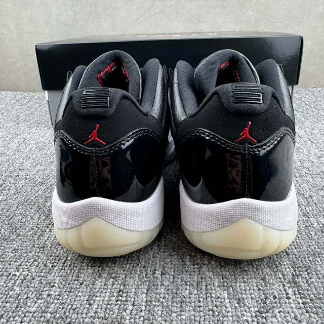Jordan 11 sneakers with black upper, red Jumpman on heel, white midsole, cream outsole
