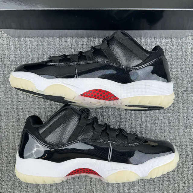 Jordan 11 sneakers with black upper, red logo on sole, white midsole, cream outsole