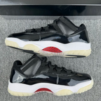 Jordan 11 sneakers with black upper, red logo on sole, white midsole, cream outsole