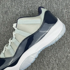 Close-up of low-top Jordan 11 sneaker side, cream mesh and navy glossy panel