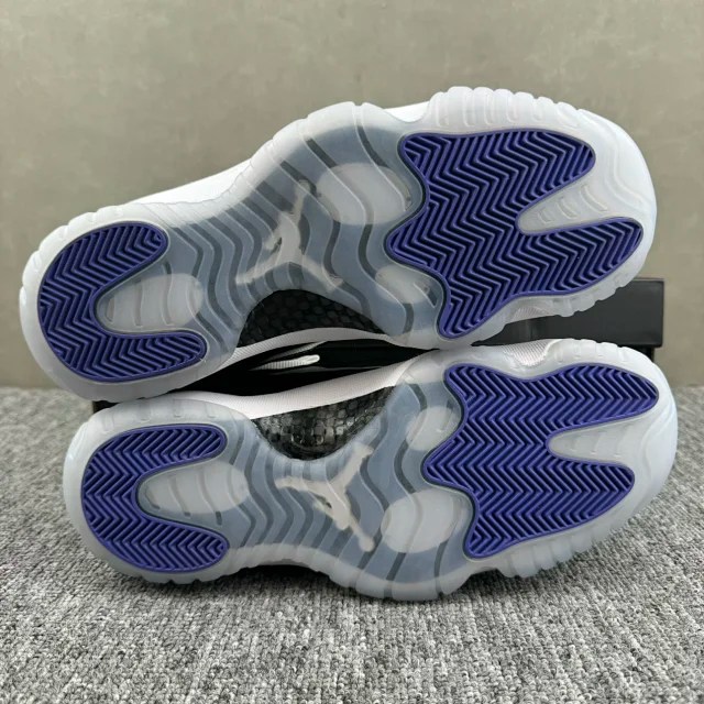 White and black low-top sneakers with blue treaded outsole, soles facing up