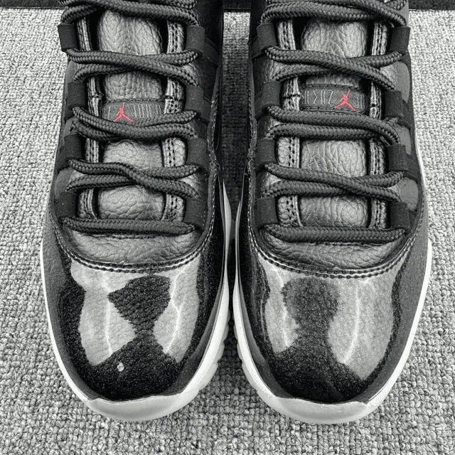 Black Jordan 11 sneakers with lace-up eyelets and gray pattern print, red Jumpman