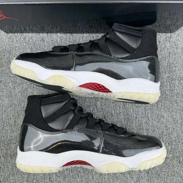 Black Jordan 11 high-top sneakers with side panels, red accent, white midsole