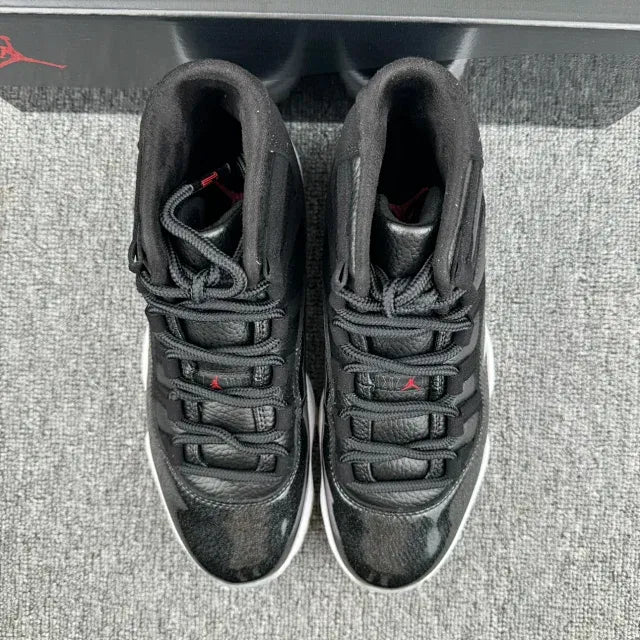 Black Jordan 11 sneakers with lace-up top, textured panels, red accents, white sole