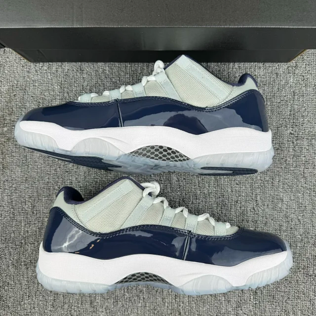 Pair of low-top Jordan 11 sneakers, cream upper with navy panels, white midsole