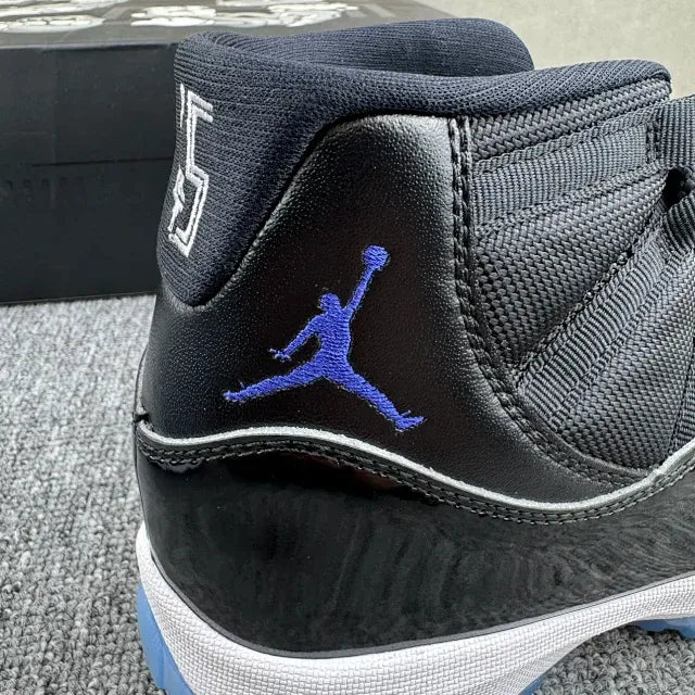 Black high-top sneaker side view with blue Jumpman logo, white midsole, blue accents.