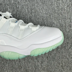 Close-up of white sneaker upper with laces, stitching, and green sole edge