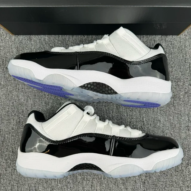 White and black low-top sneakers on gray fabric with blue-accented outsole