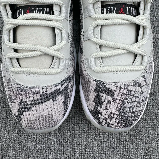 Low-top sneaker front view with white laces and toe box, plus gray-and-black snakeskin overlay