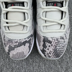Low-top sneaker front view with white laces and toe box, plus gray-and-black snakeskin overlay
