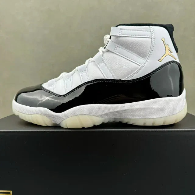 White and black Jordan 11 sneaker with gold Jumpman logo and off-white sole