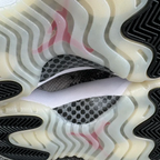 Shoe outsole close-up with tread pattern and sidewall detail in off-white and black