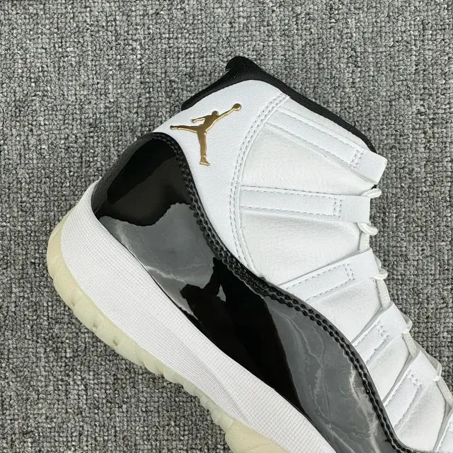 White Jordan 11 low-cut sneaker with gold Jumpman logo and black patent panel