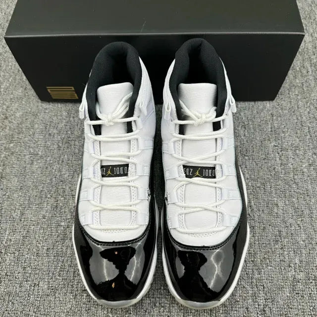 White and black Jordan 11 sneakers with lace-up closure and gold logos