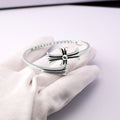 Chrome bangle bracelet with bow-shaped clasp and rhinestone pavé band