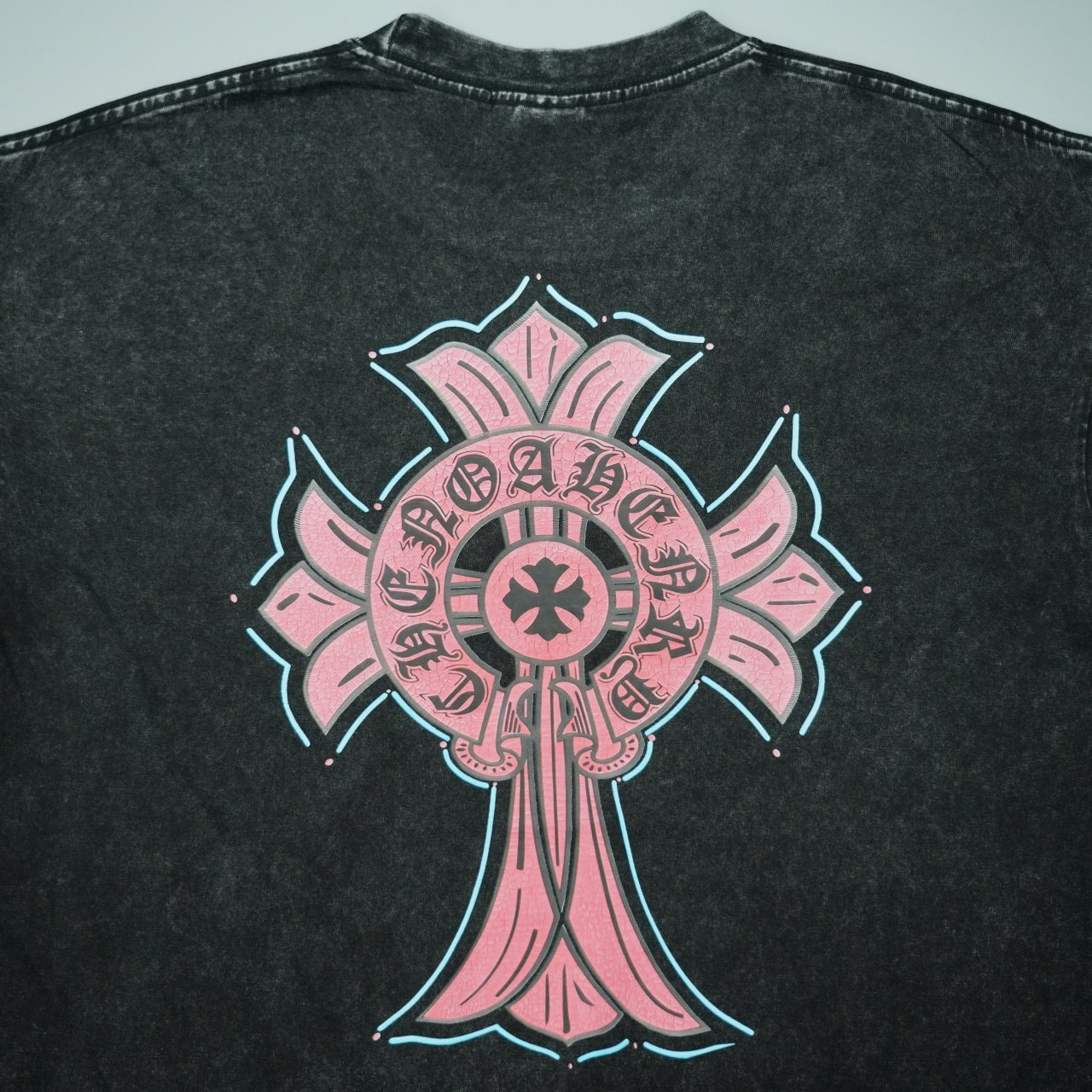 Black T-shirt back with large pink cross graphic outlined in neon blue
