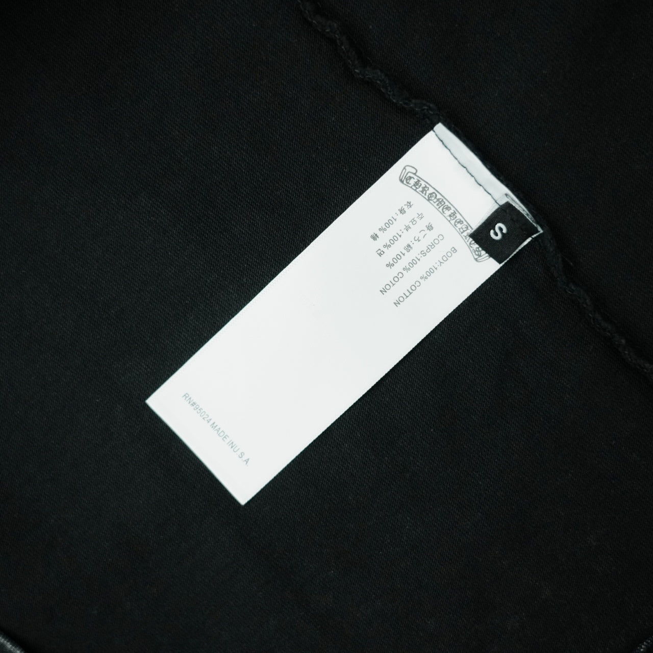 Black T-shirt care label with size S on inner collar