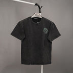 Black graphic T-shirt with small green emblem on left chest and crew neck