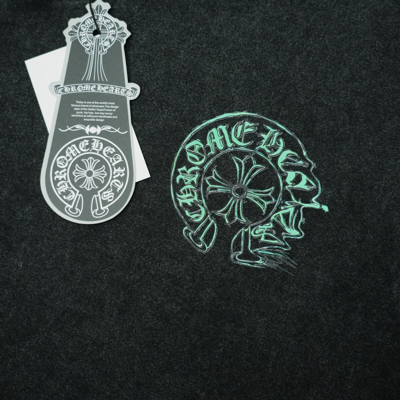 Black T-shirt with green head graphic print and attached white hang tag