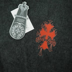 Dark T-shirt with orange-red cross-style graphic and white hang tag