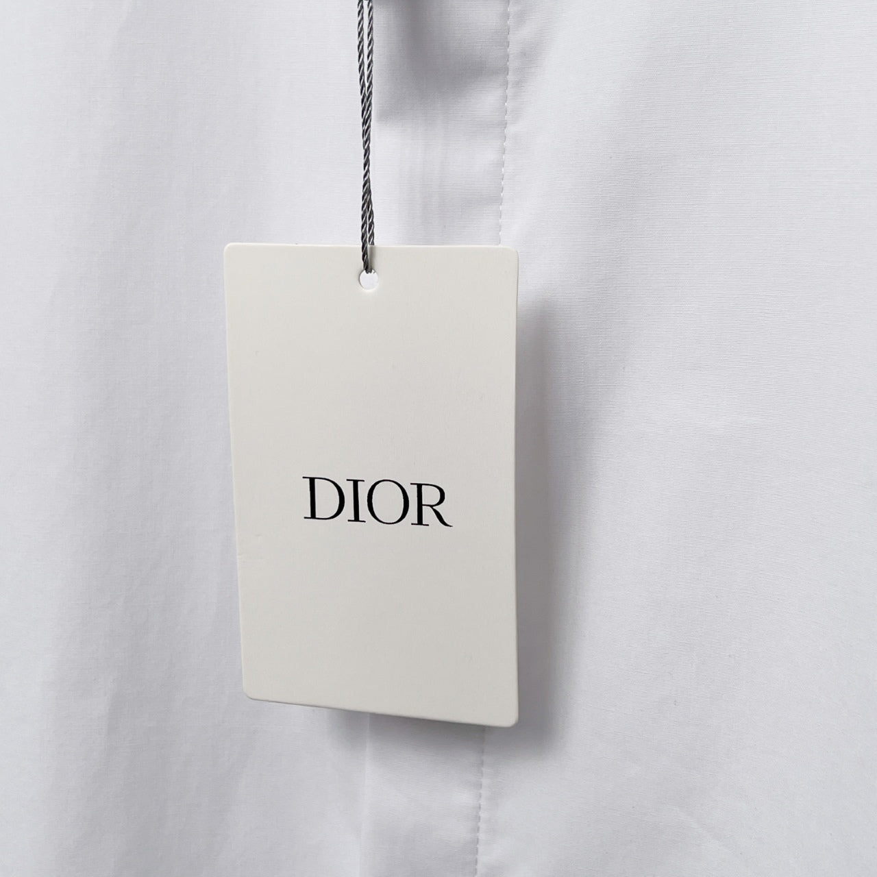 Dior clothing tag on white shirt, DIOR logo on hanging label