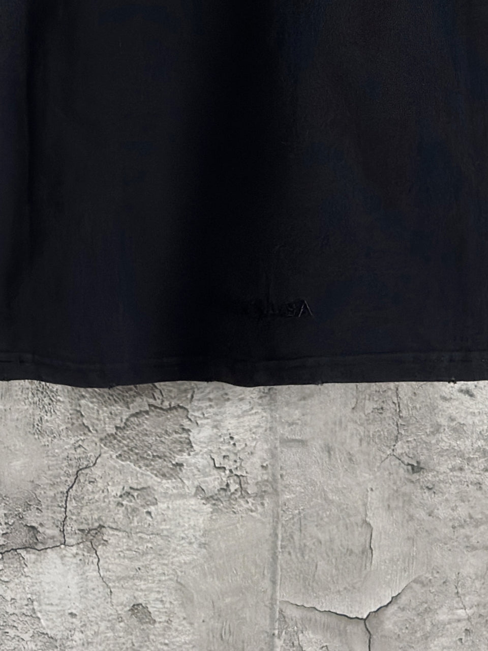 Black long-sleeve T-shirt hem with small embossed logo detail