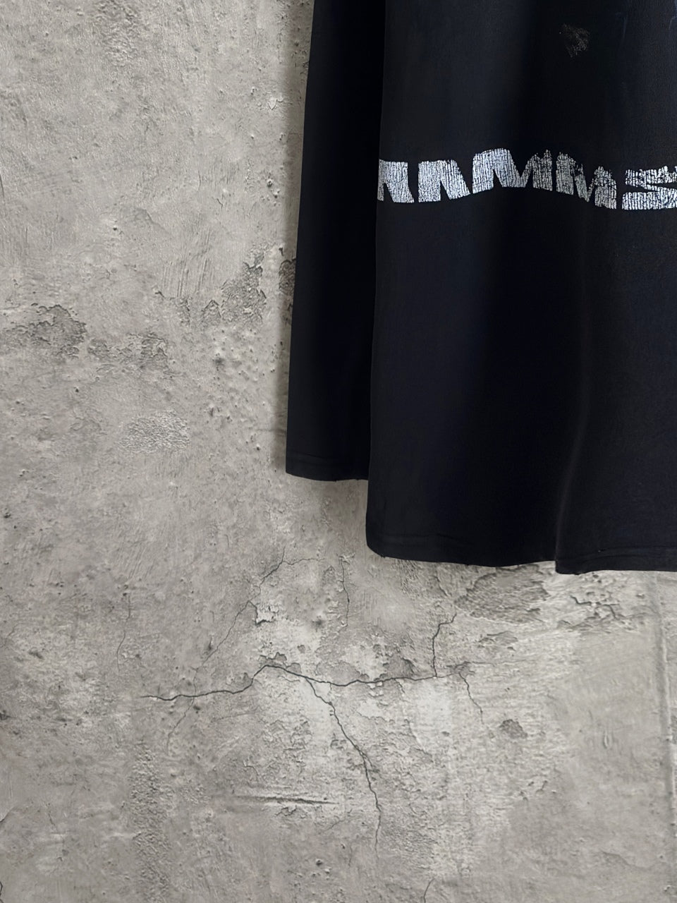 Black long-sleeve T-shirt side view with partial white graphic lettering