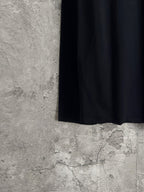 Long-sleeve crewneck shirt hem and side profile, hanging on dark fabric