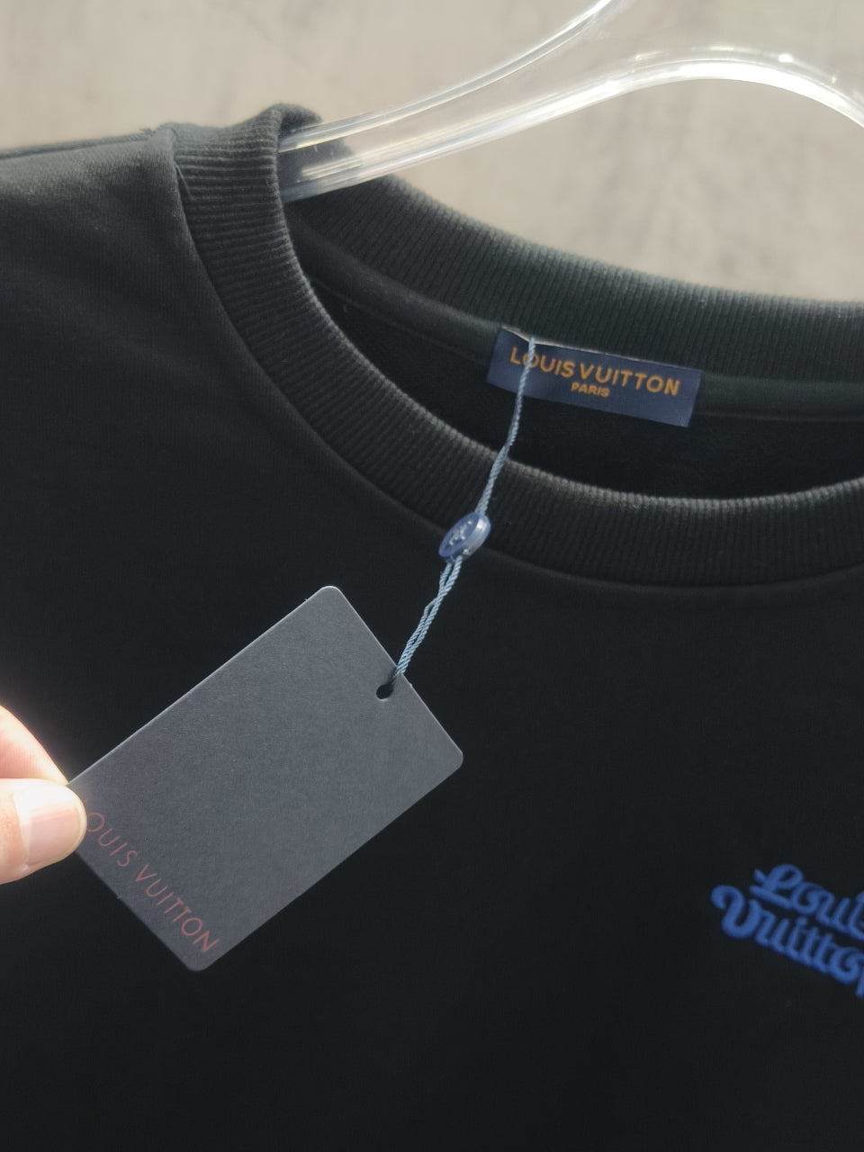 Dark crewneck sweatshirt with hanging product tag at the collar