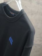Dark long-sleeve crewneck sweatshirt with small blue logo on the sleeve