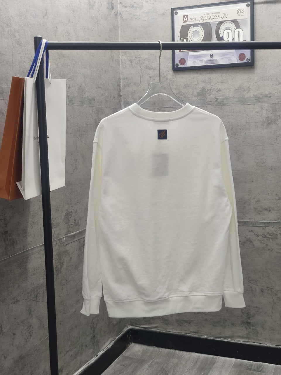 White long-sleeve sweatshirt on hanger, back view