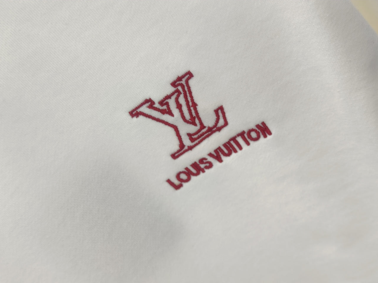 Red Louis Vuitton LV logo and text on white sweatshirt fabric