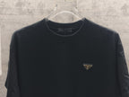 Dark short-sleeve T-shirt with triangular logo patch at chest