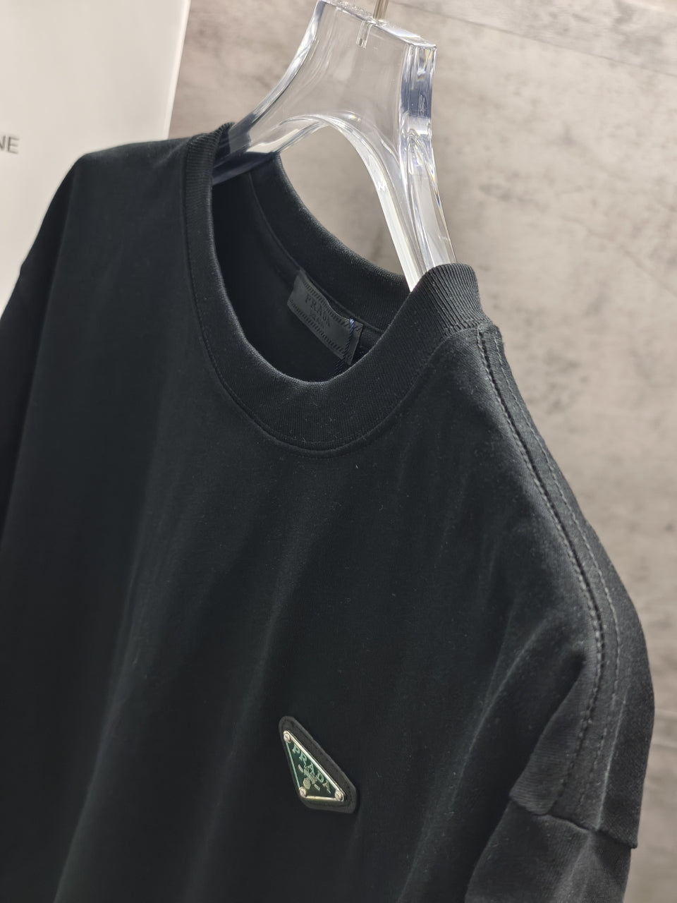 Dark short-sleeve T-shirt with logo patch on chest, side view