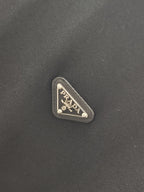 Triangular Prada logo patch on dark fabric