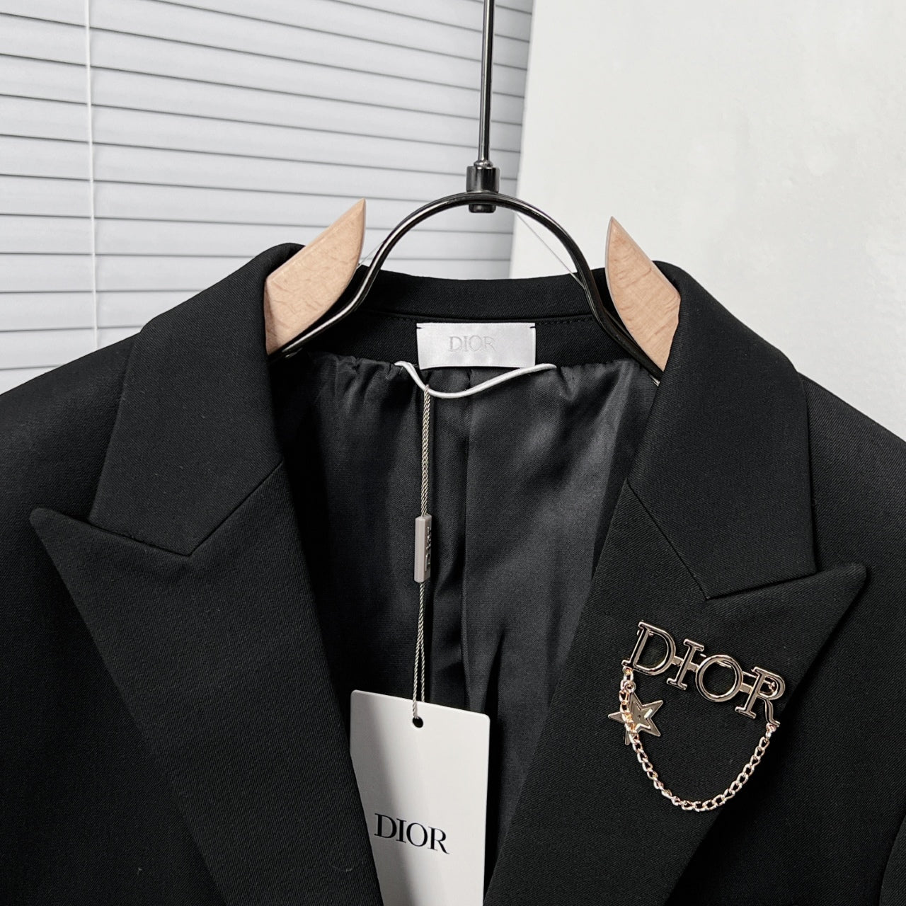 Black Dior suit jacket with buttoned front, star chain pin detail, and hanging tag