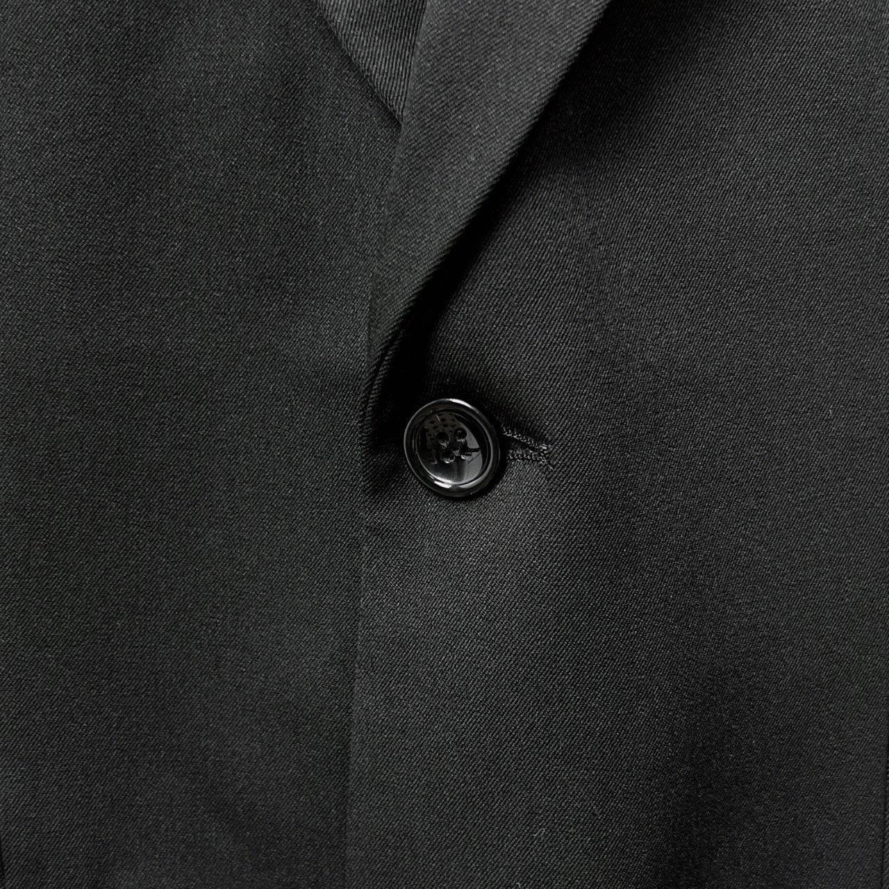 Black suit jacket close-up of round button and lapel seam