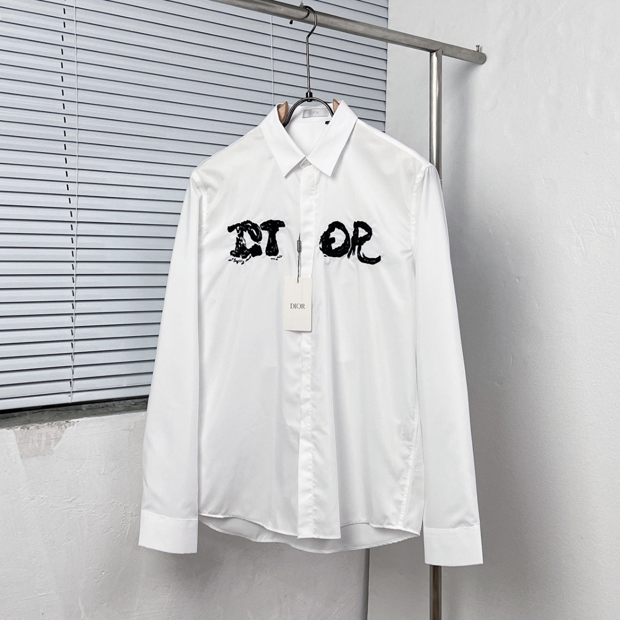 White button-up dress shirt with black graphic logo on chest
