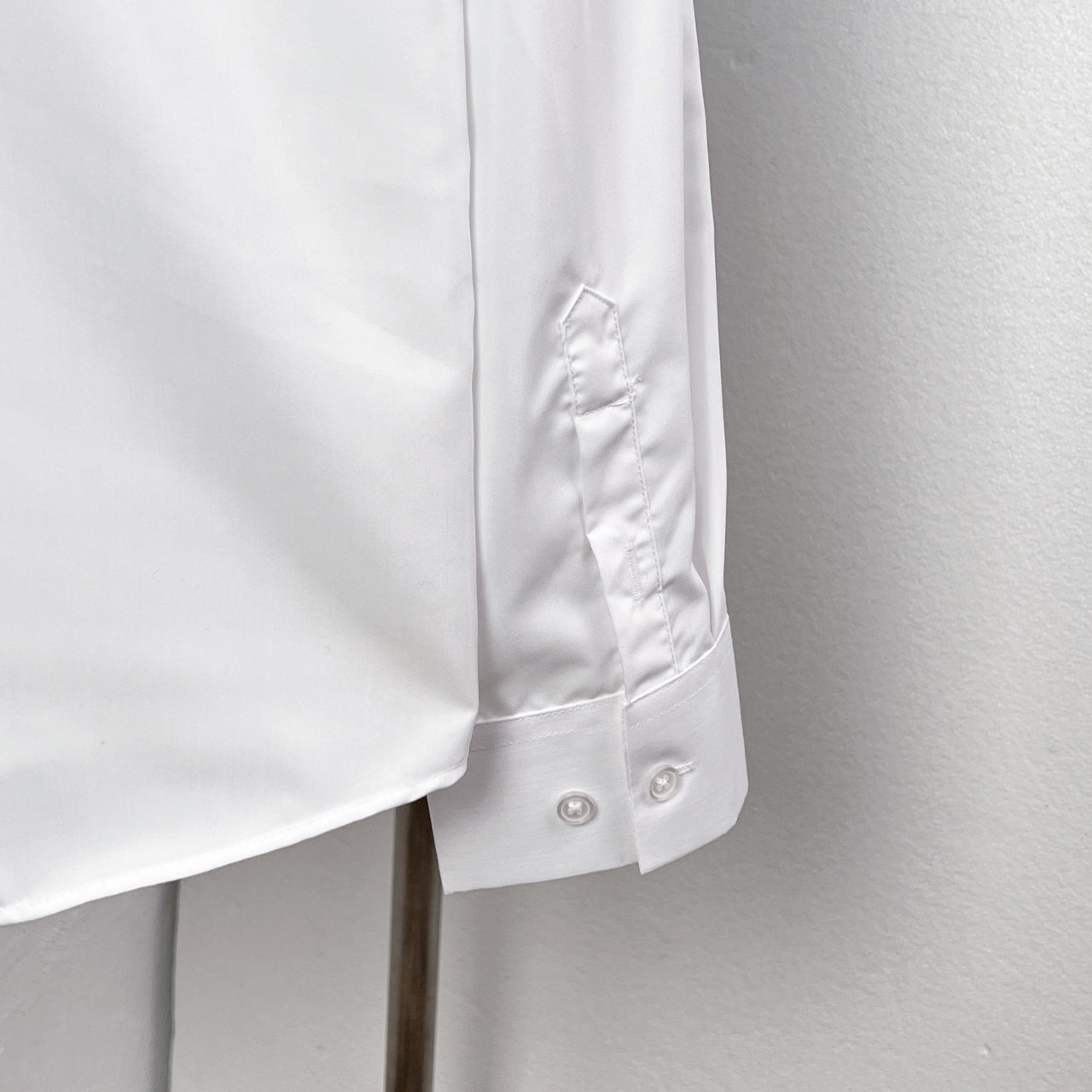 White button-up dress shirt cuff with small embroidered emblem