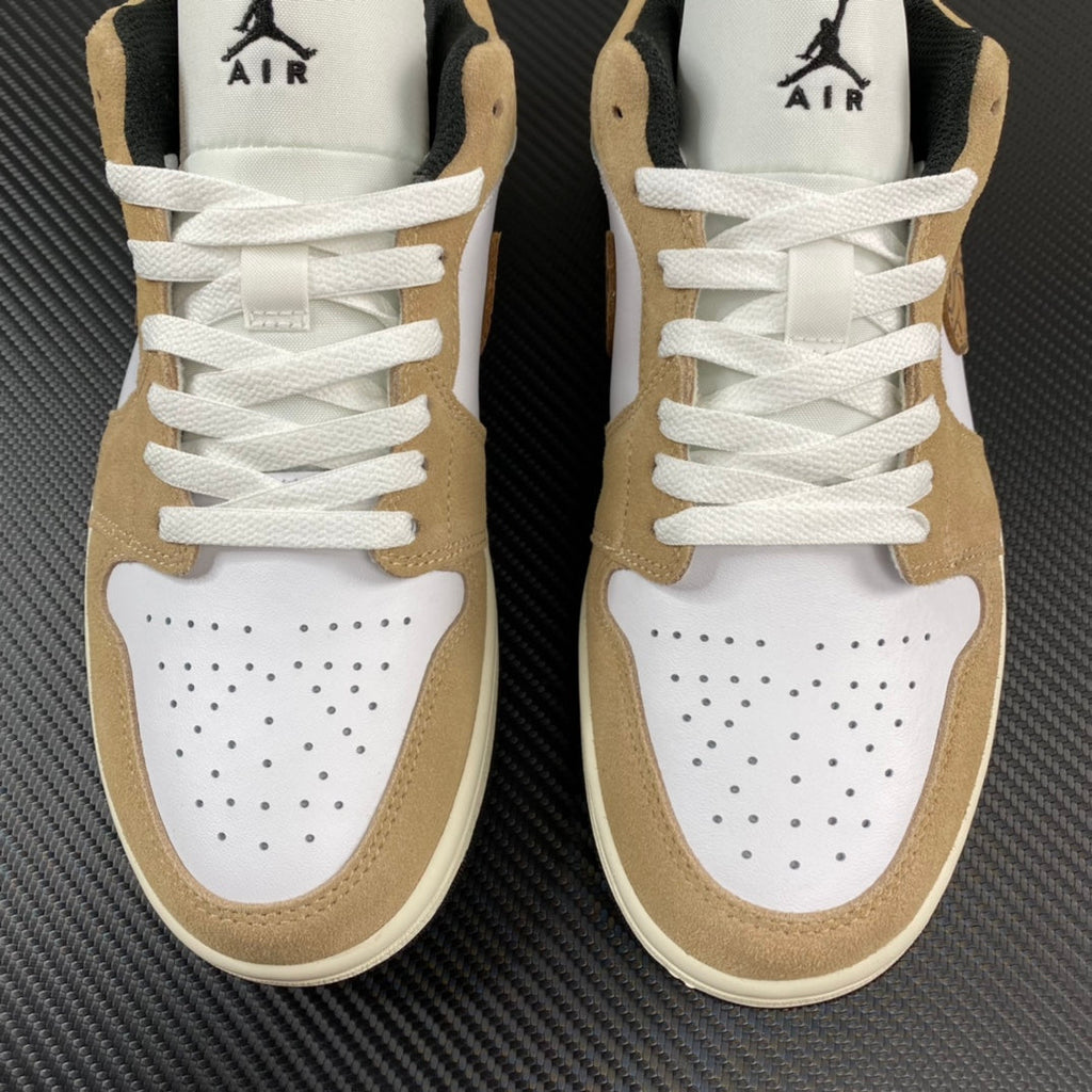 Pair of tan and white low-top sneakers with perforated toe and white laces
