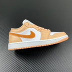 Air Jordan 1 Low sneakers with white, tan, and orange panels; orange lace eyelets