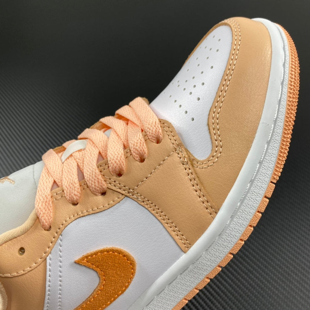 Air Jordan 1 Low sneakers close-up: tan leather and white toe box with orange laces