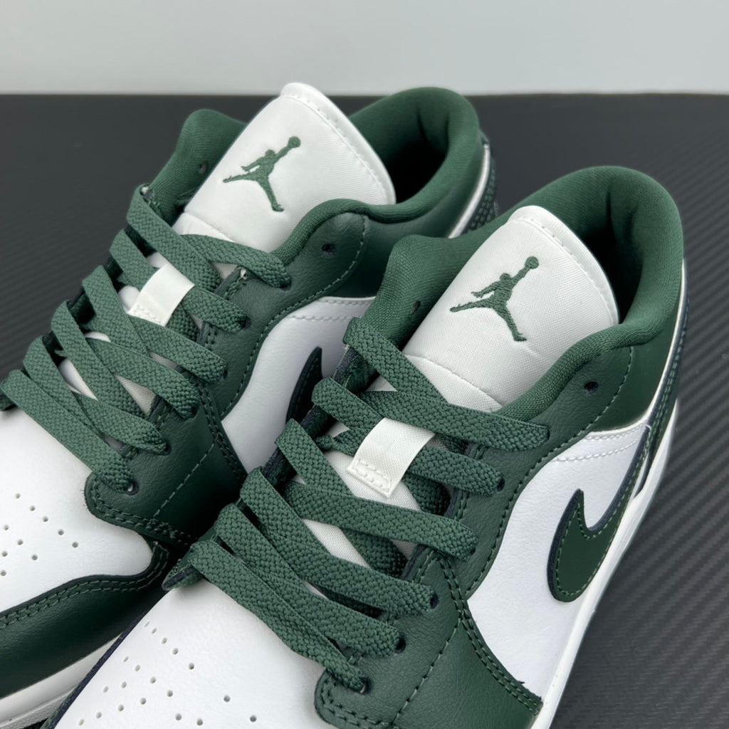 Low-top sneakers angled close-up with dark green swoosh and white quarter panels