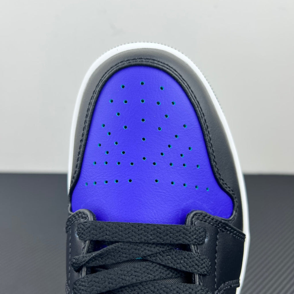 Low-top sneaker toe area with perforations, blue-purple panel, dark laces, and white trim.