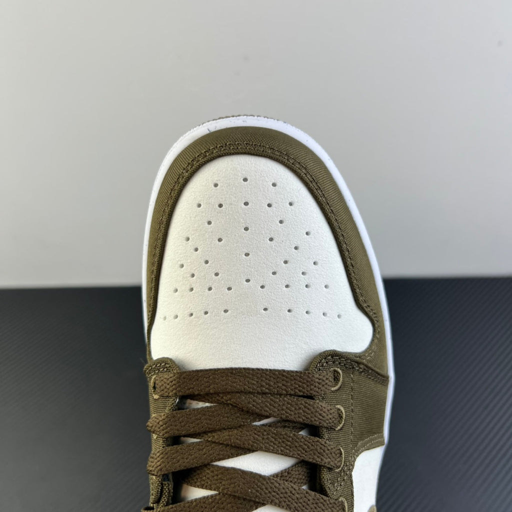 Close-up of low-top sneaker toe and laces in olive with perforated white panel