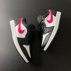 Two black and white low-top sneakers with red swooshes and side panels