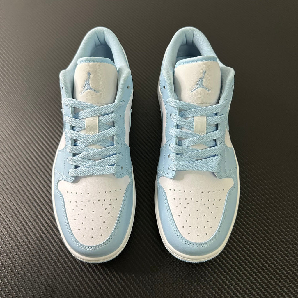 Pair of light blue and cream low-top sneakers with laces and perforated toe